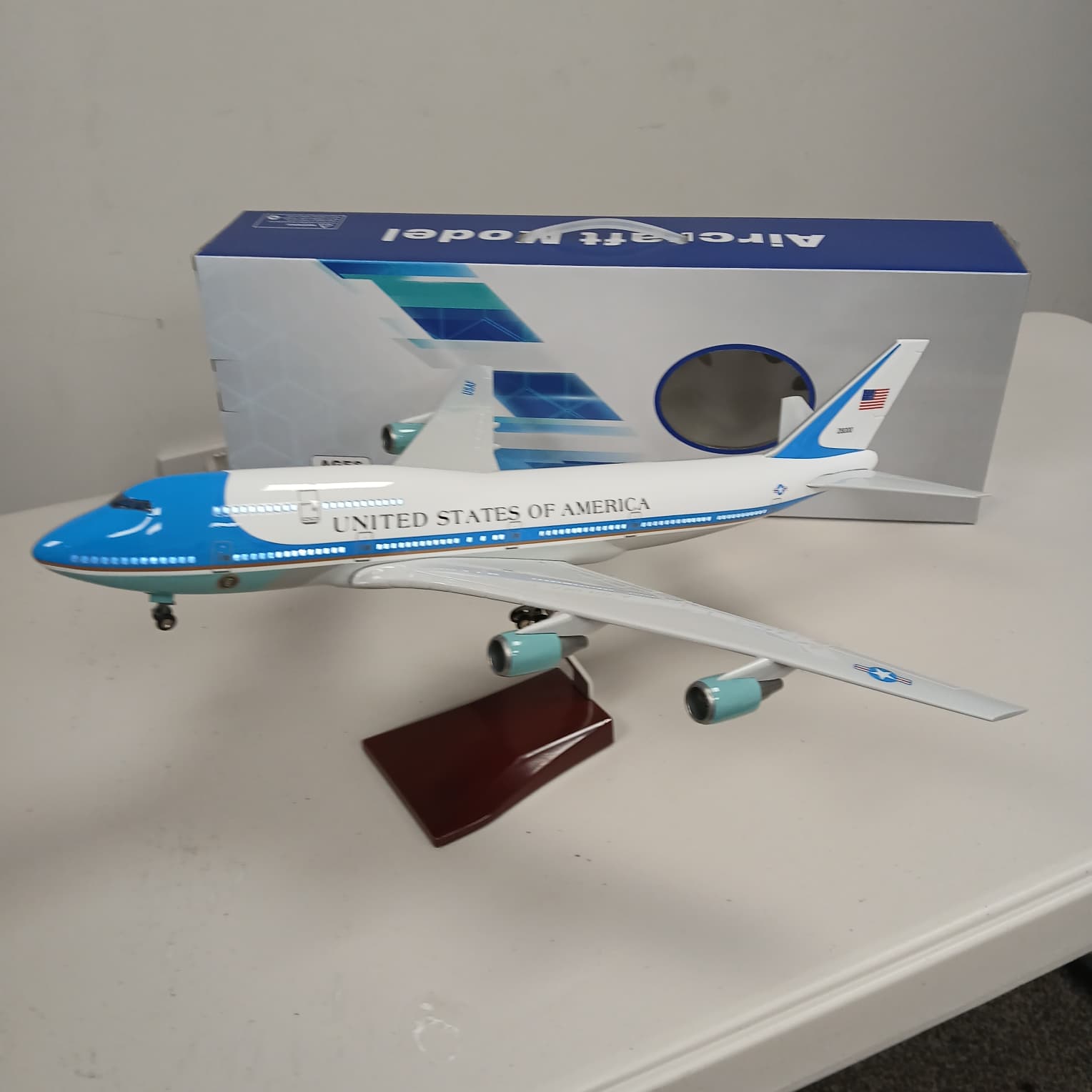 Model airplane of a United States aircraft on a white surface with a branded box in the background.